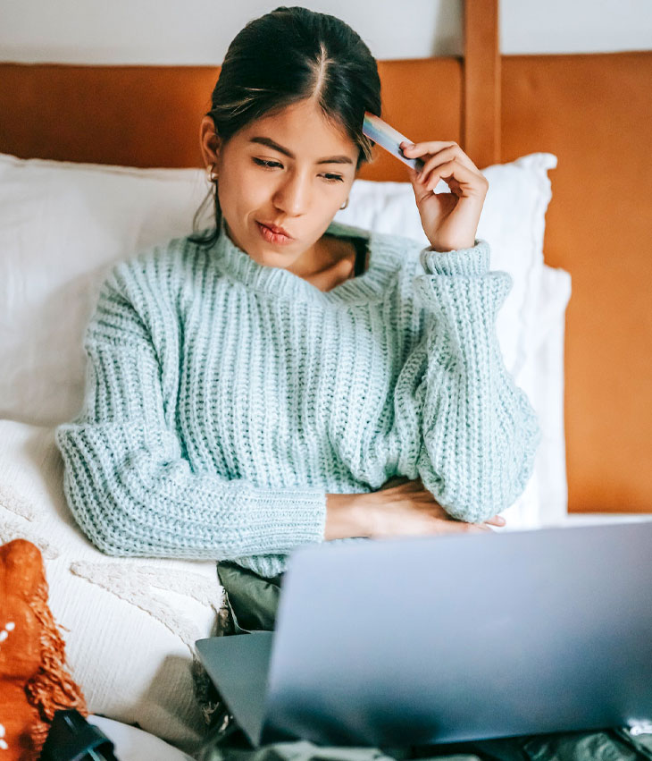 Hesitant young woman doing online shopping