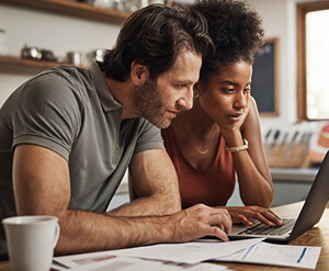 Couple looking at laptop together browsing solutions in their kitchen