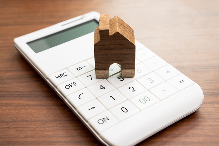 Wooden house ornament on white calculator