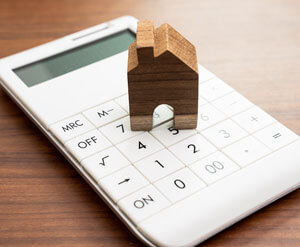 Wooden house ornament on white calculator